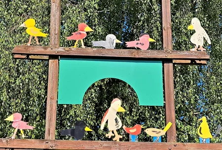 Bunte Holzvögel sitzen auf zwei Holzmasten