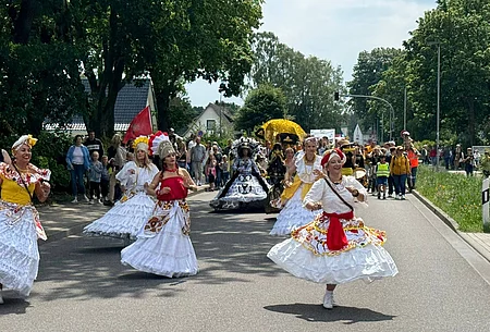 Mit langen bunten Kleidern festlich gewandete Tänzerinnen vor Festumzug
